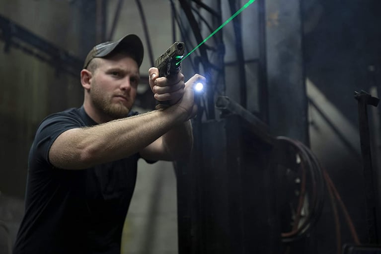 Photo of a man aiming a pistol with a laser sight